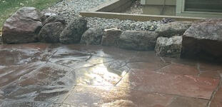 Small moss rock boulders tucked together around a newly washed flagstone patio